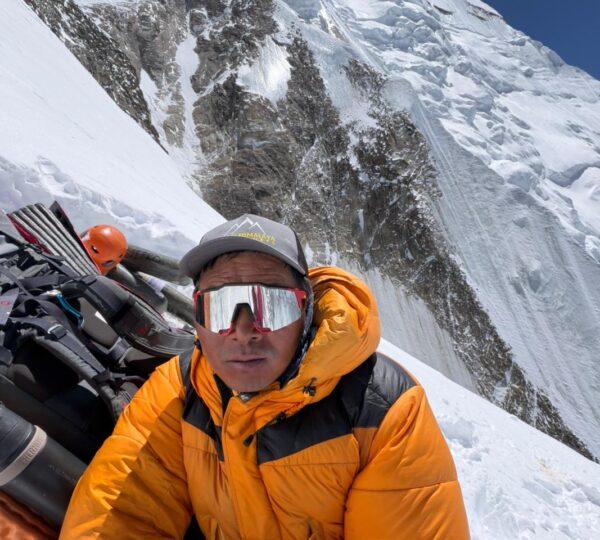 Climber at Annapurna I Camp 3 with steep snow slope in background