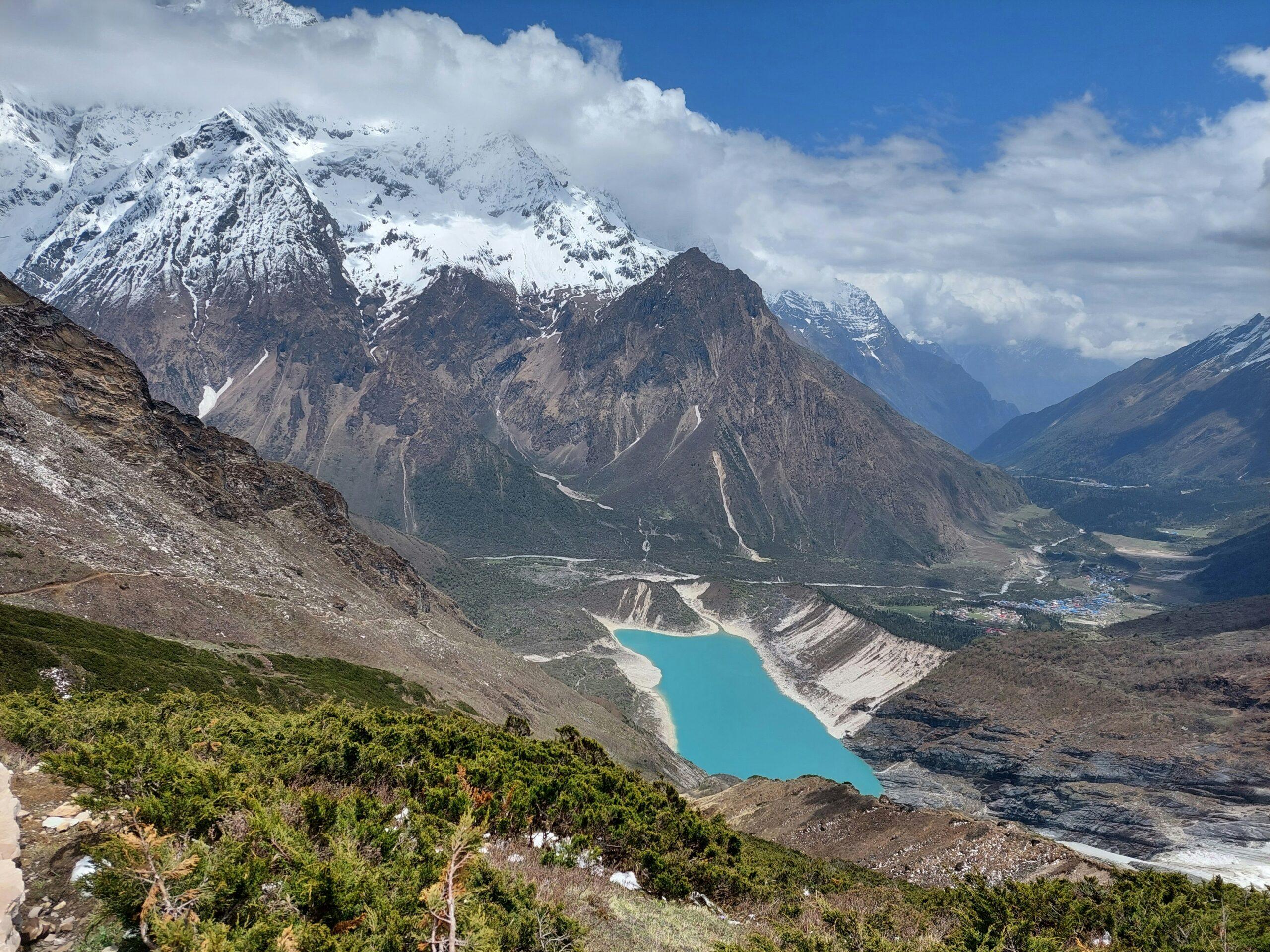 Turquoise glacial lake beside a village on the Manaslu Circuit Trek